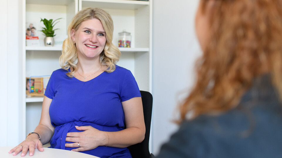 Beratung Eine schwangere Frau in blauem Tshirt während einer Beratung.